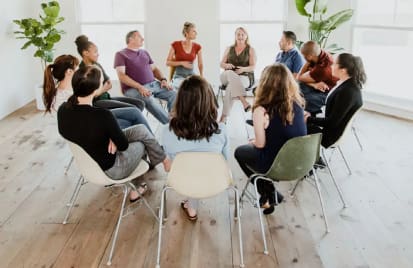 A group of people sitting in chairs around each other.