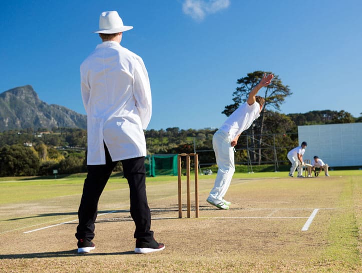 A man in white shirt and hat playing cricket.