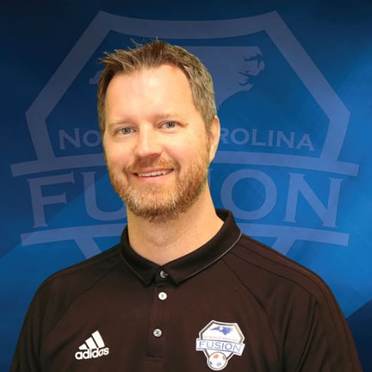 A man standing in front of a blue background.