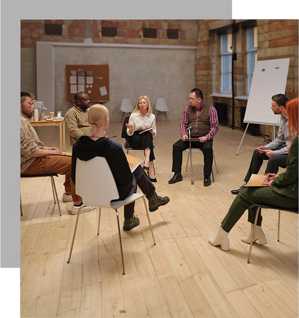 A group of people sitting in chairs around a white board.