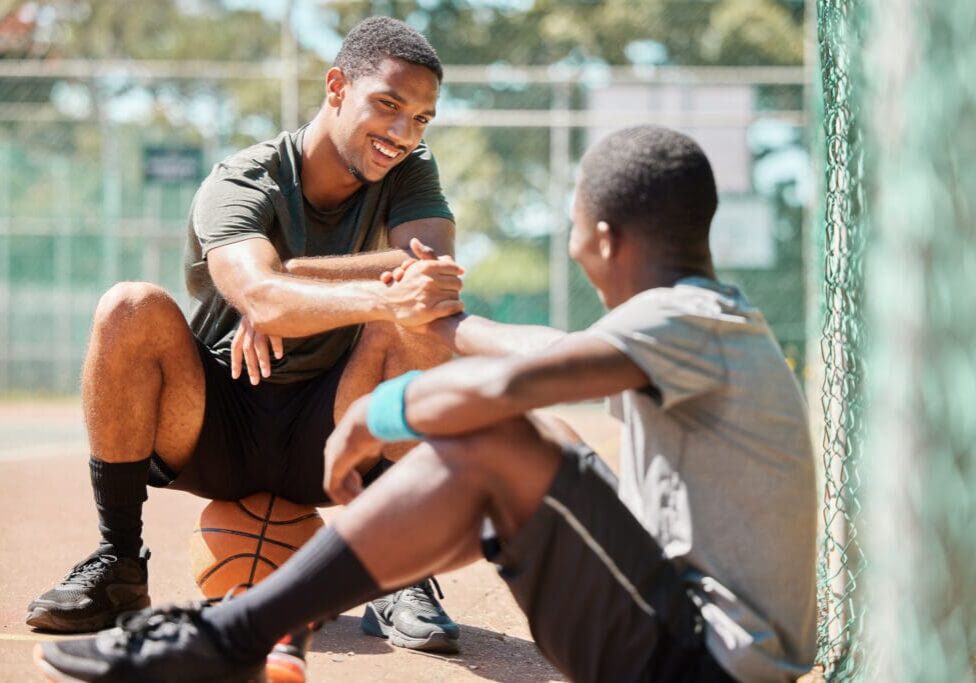 Teamwork, sports and friends with black man on basketball court holding hands for support, congratu.