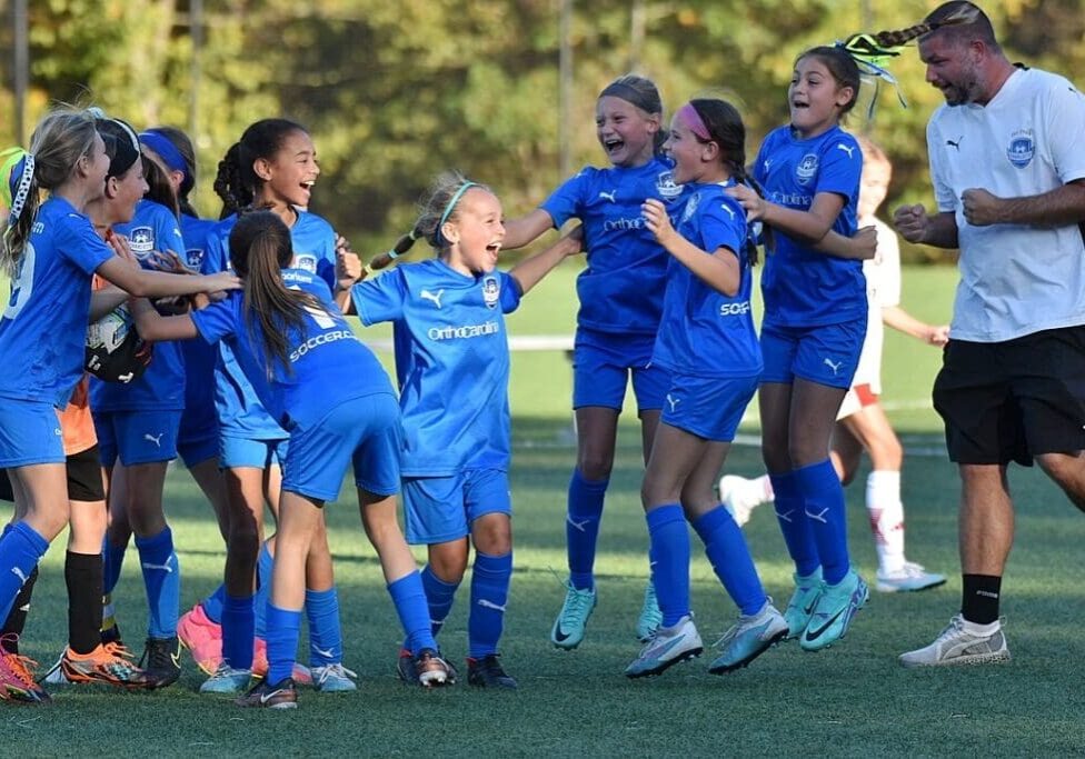 A group of girls in blue soccer uniforms celebrating.